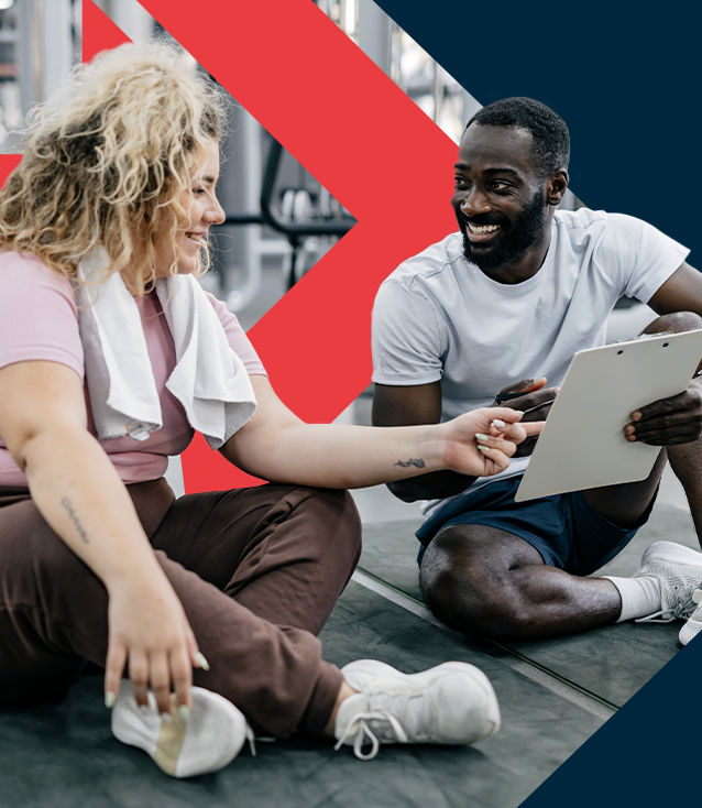ACE Weight Management Specialist coaching an overweight client in a gym, reviewing progress data on a clipboard